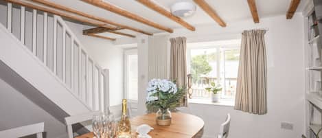 Uma mesa de jantar de madeira com uma garrafa de champanhe, copos e um arranjo decorativo.