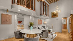 Un salon moderne avec une table ronde blanche, des fauteuils gris, un canapé et un lustre.
