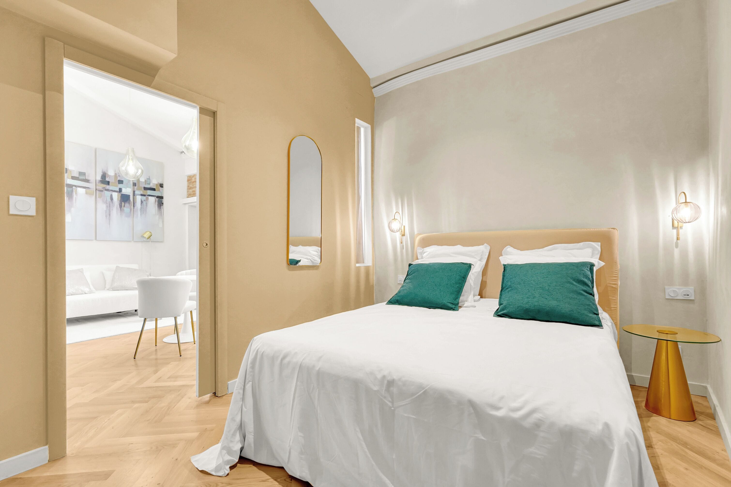 Quarto moderno com uma cama grande, uma mesa de cabeceira e um espelho.