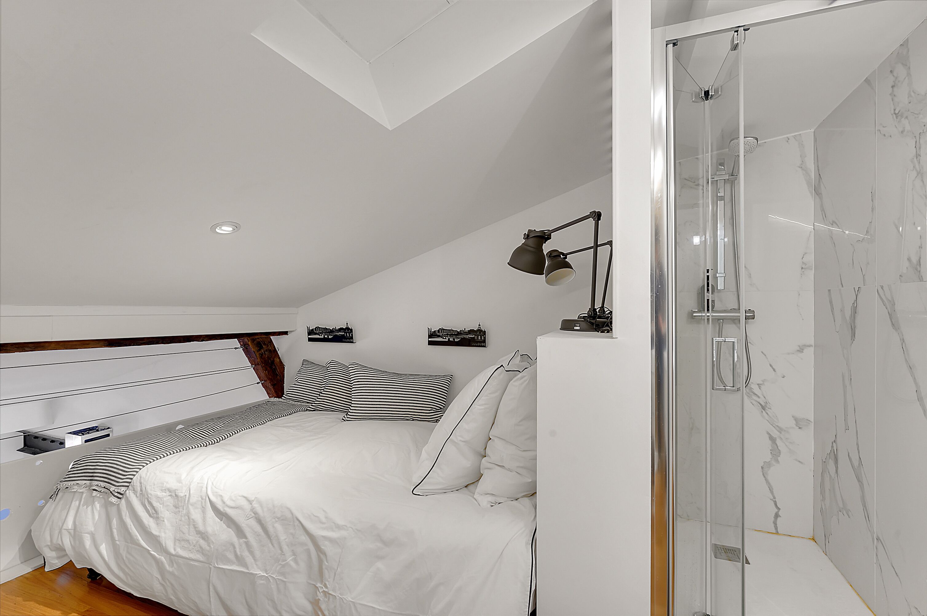 Une chambre à coucher avec un lit, une table de chevet, une lampe, une douche et un mur en marbre.