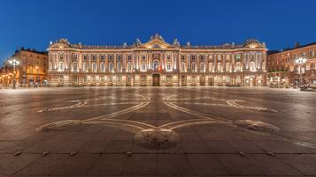 A grand, illuminated building with a symmetrical facade and a central courtyard.