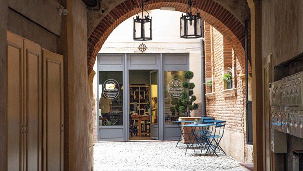 Un portail en arc conduisant à une boutique dont l’enseigne porte l’inscription « Capitole ».