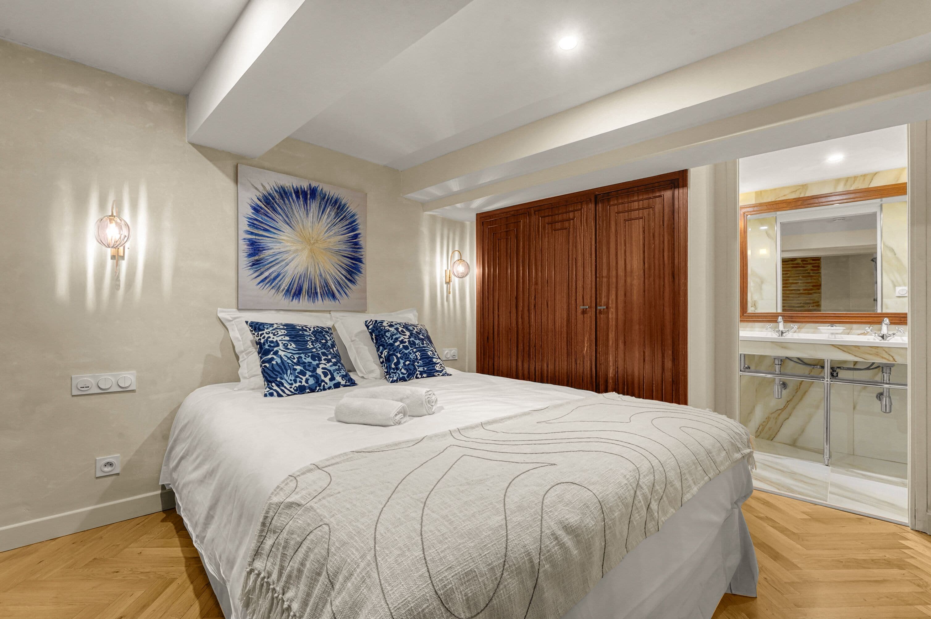 Quarto com cama grande, guarda-roupa de madeira e banheiro com box de vidro.