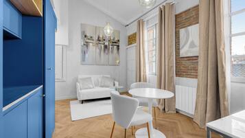 A modern living room with a white sofa, a round white table, and a blue cabinet.