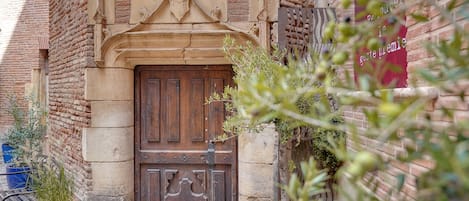 Un edificio rústico con puerta de madera, paredes de piedra y plantas en macetas.