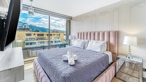 A modern hotel room with a large bed, a TV, a glass table, and a view of the cityscape. - Stylish Art 2B w/ Balcony, Parking & Wifi (Santiago)