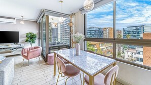 A modern apartment with a dining area, a flat-screen TV, and large windows offering a city view. - Stylish Art 2B w/ Balcony, Parking & Wifi (Santiago)