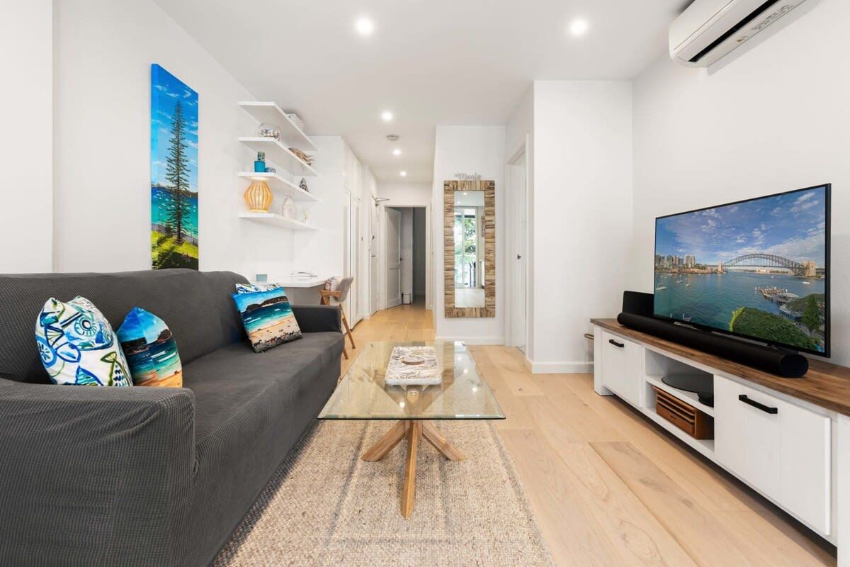 A modern living room with a sofa, coffee table, TV, and shelves.
