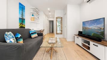 A modern living room with a sofa, coffee table, TV, and shelves.