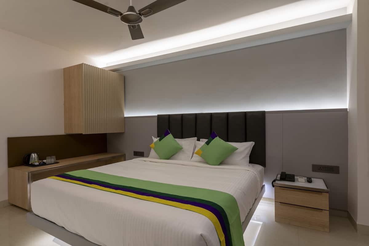 Habitación de hotel moderna con una cama grande, una mesita de noche, un armario de madera y un ventilador de techo.