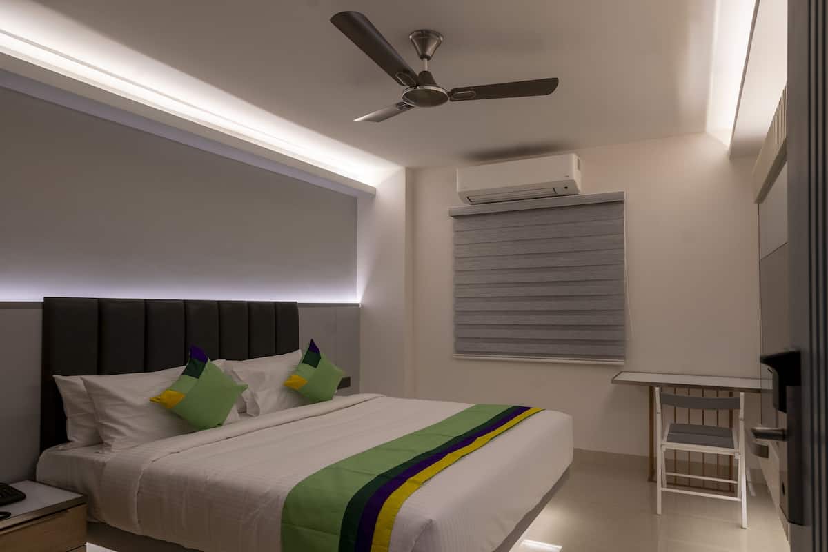 Un dormitorio moderno con una cama, un ventilador de techo, un equipo de aire acondicionado y una mesita.