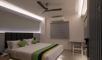 Quarto moderno com cama, ventilador de teto, ar condicionado e uma pequena mesa.