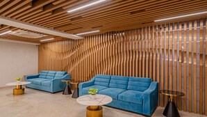 A modern interior with two blue sofas, round tables, and a wooden slatted wall. - Treebo Premium D Consulate (Hyderabad)