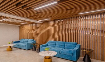 A modern interior with two blue sofas, round tables, and a wooden slatted wall.