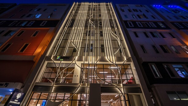 A modern hotel building with a prominent vertical design, multiple floors, and a mix of glass and metal elements. - Treebo Premium D Consulate (Hyderabad)