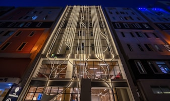 A modern hotel building with a prominent vertical design, multiple floors, and a mix of glass and metal elements.
