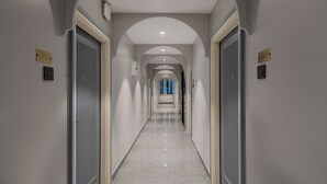 A long, narrow hallway with arched ceilings and doors on either side, leading to a room with a blue window. - Treebo Premium D Consulate (Hyderabad)
