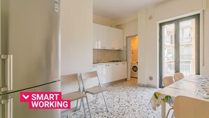 A compact kitchen with white cabinets, a dining table with chairs, and a tiled floor. - Casa Campione by Wonderful Italy (Bari)