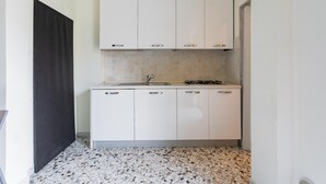 A compact kitchen with white cabinets, a tiled backsplash, and a gas stove. - Casa Campione by Wonderful Italy (Bari)