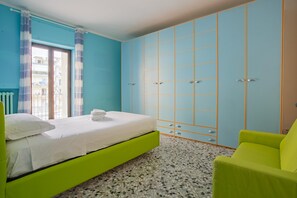 Una camera da letto con un letto, una sedia verde e un armadio blu.