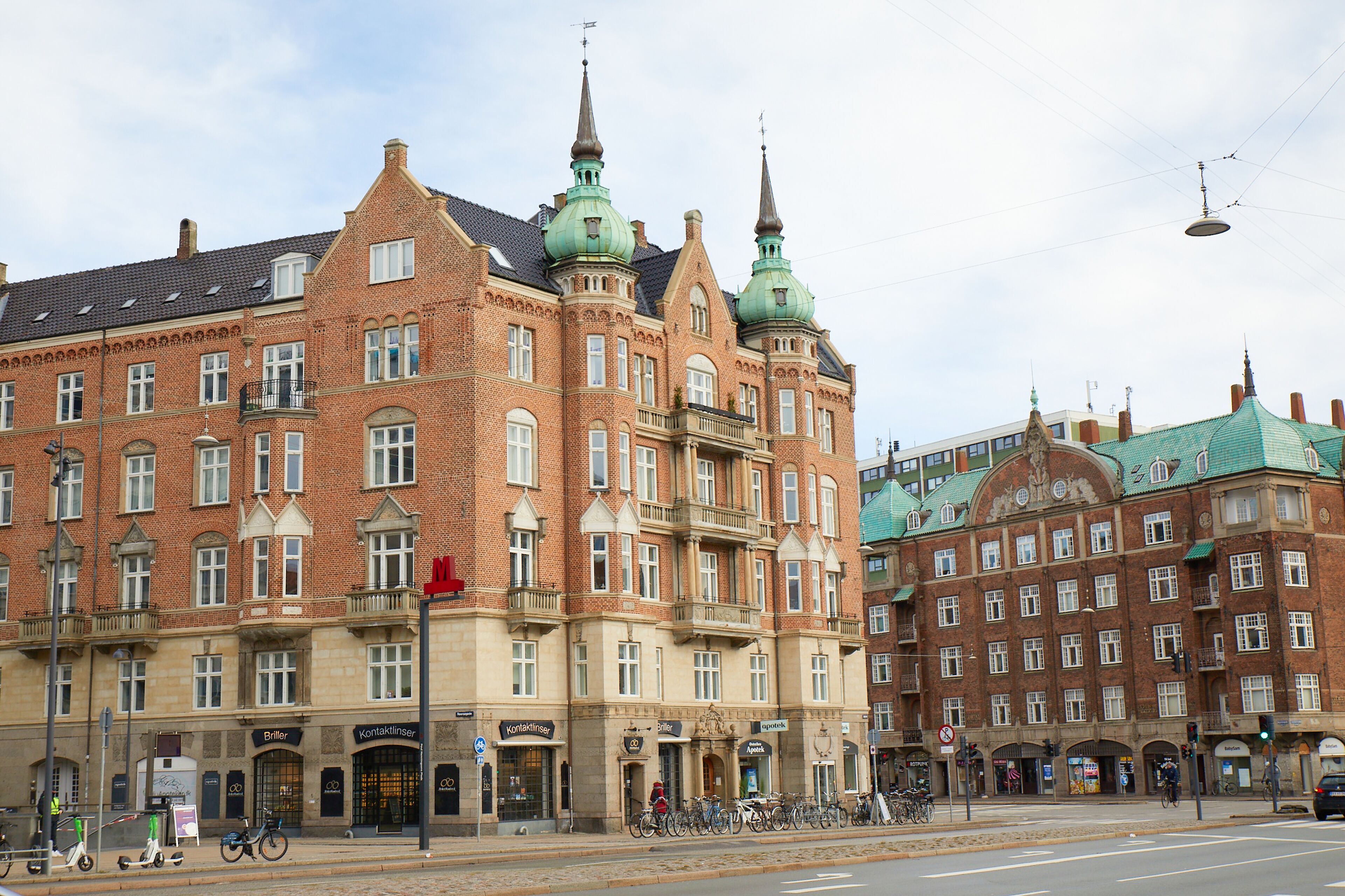 A historic building with multiple stories, large windows, and distinctive green spires.