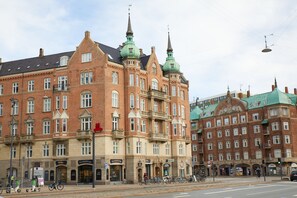 Un bâtiment historique à étages, doté de grandes fenêtres et de flèches vertes caractéristiques.