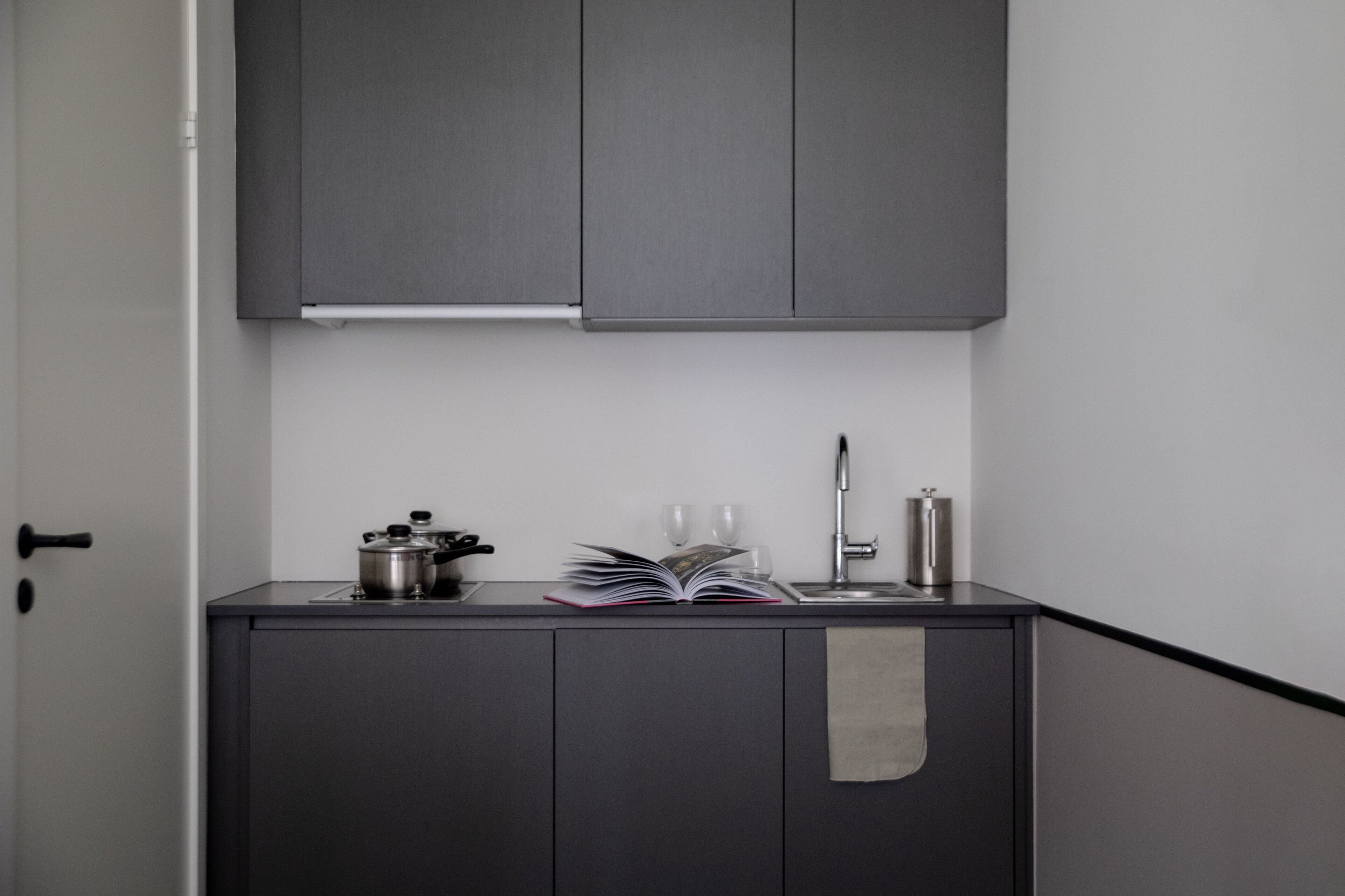 Una cocina compacta con armarios oscuros, un lavamanos de acero inoxidable y una pequeña encimera.