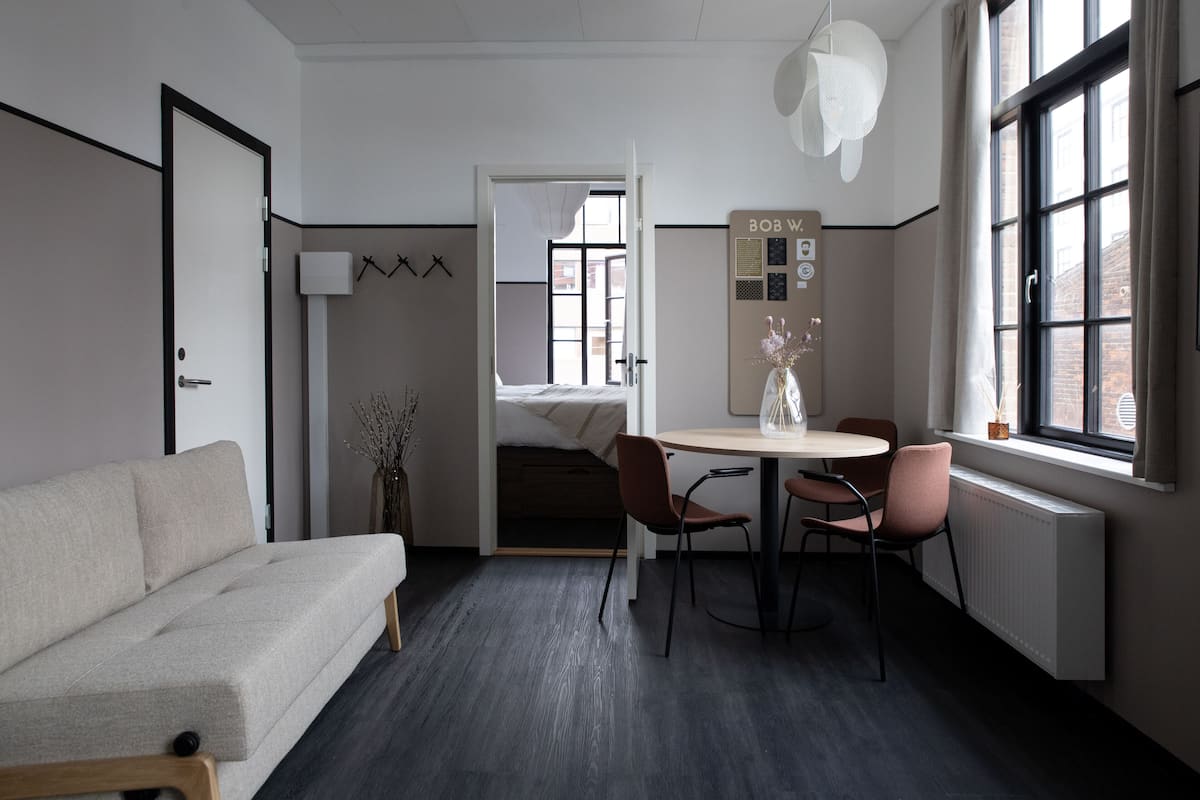 Een moderne kamer met een bank, een eettafel met stoelen, een radiator en een raam met uitzicht.