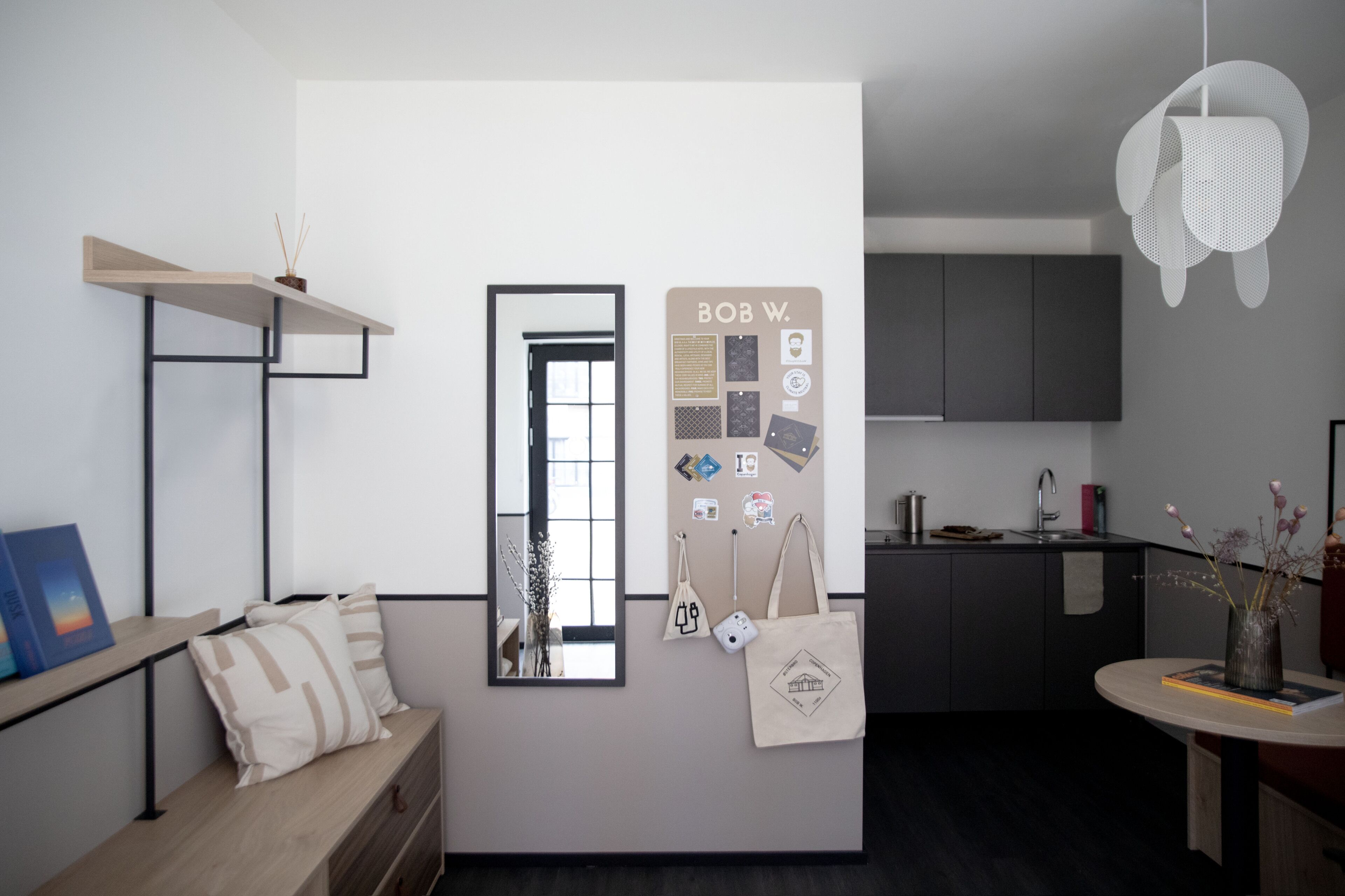 A modern kitchen with dark cabinets, a wooden countertop, and a hanging light fixture.