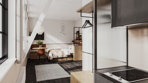 Un dormitorio moderno y funcional con cama, escritorio, silla y una pequeña zona de kitchenette.
