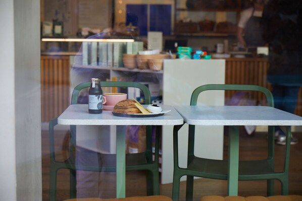 Un café avec une table dressée pour deux personnes, agrémentée d’une bouteille, d’une tasse et d’une pâtisserie.