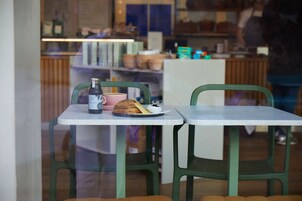 A café with a table set for two, featuring a bottle, a cup, and a pastry.