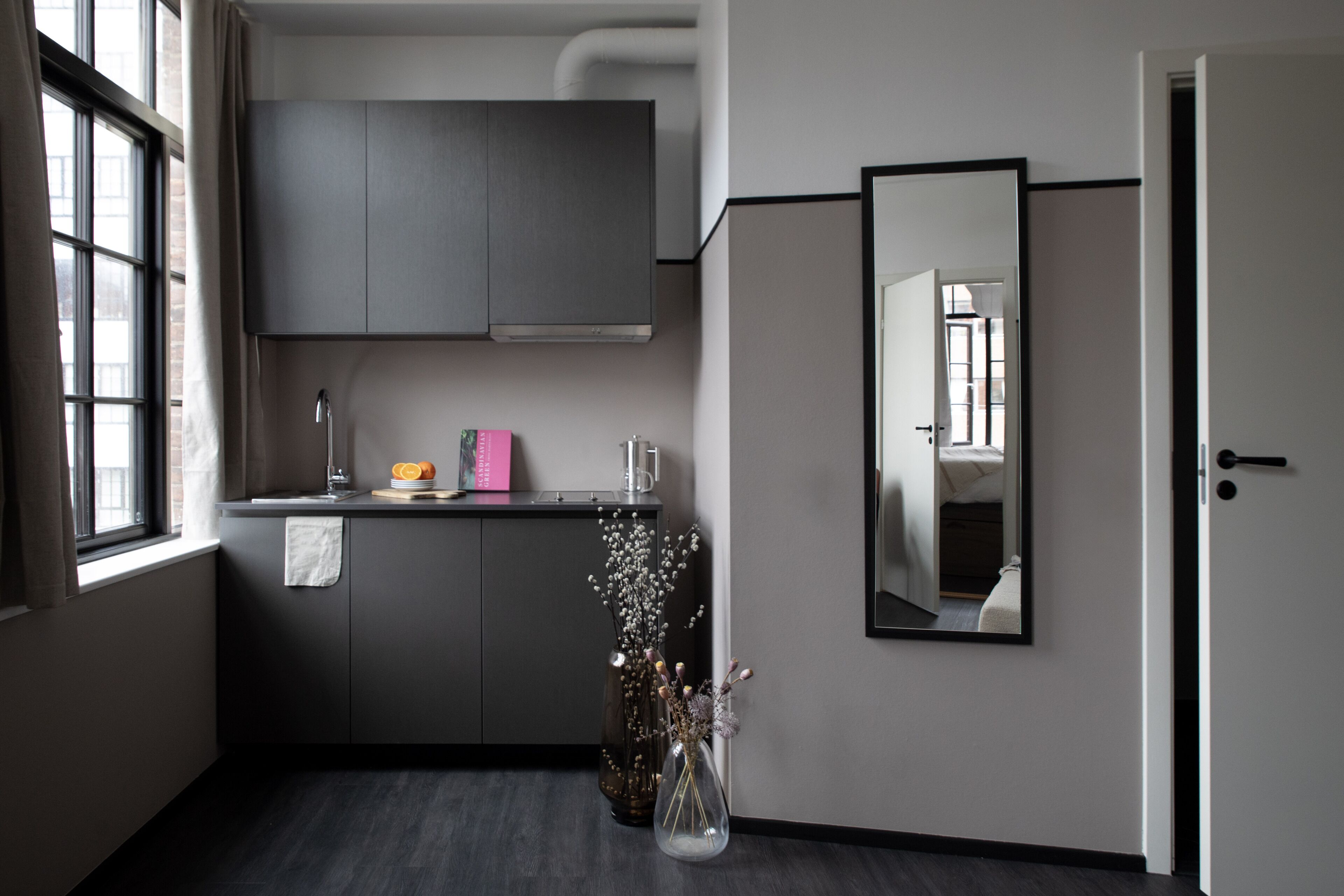 A modern kitchen with dark cabinets, a countertop, and a vase with flowers.