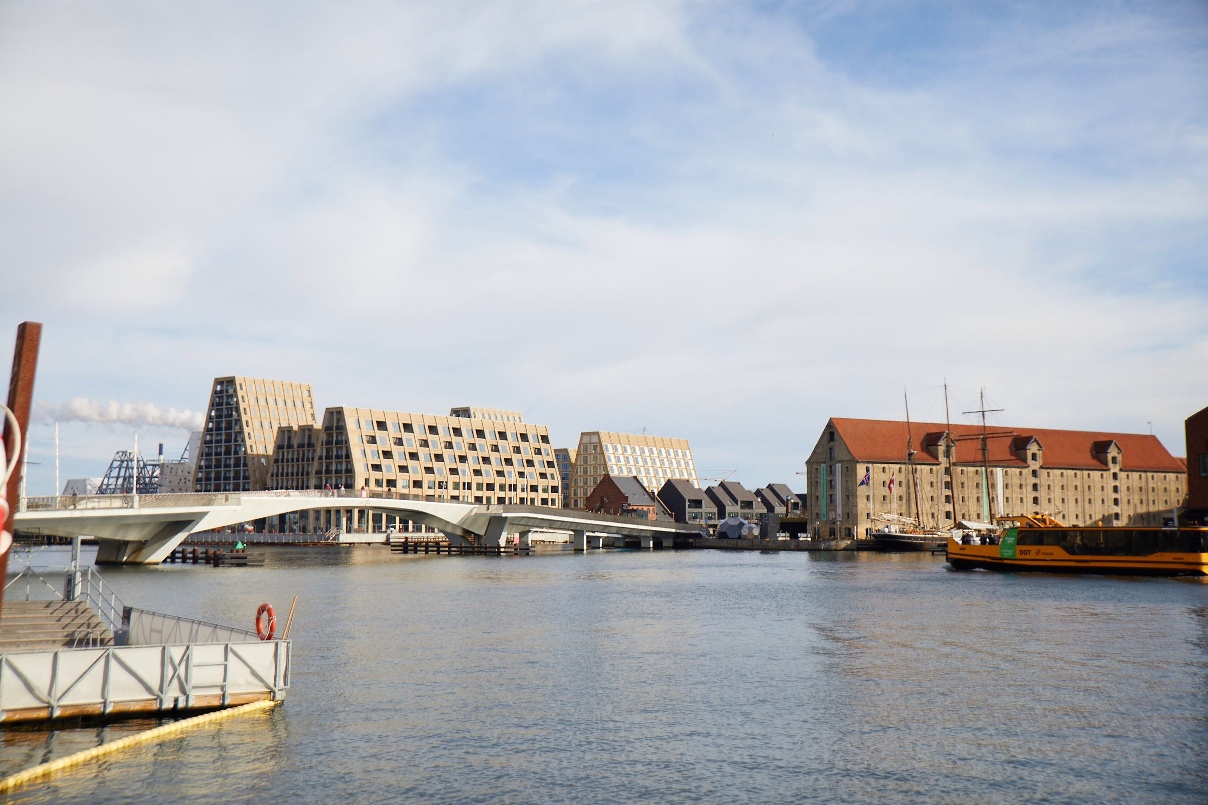 A waterfront view with a bridge, buildings, and a boat dock.