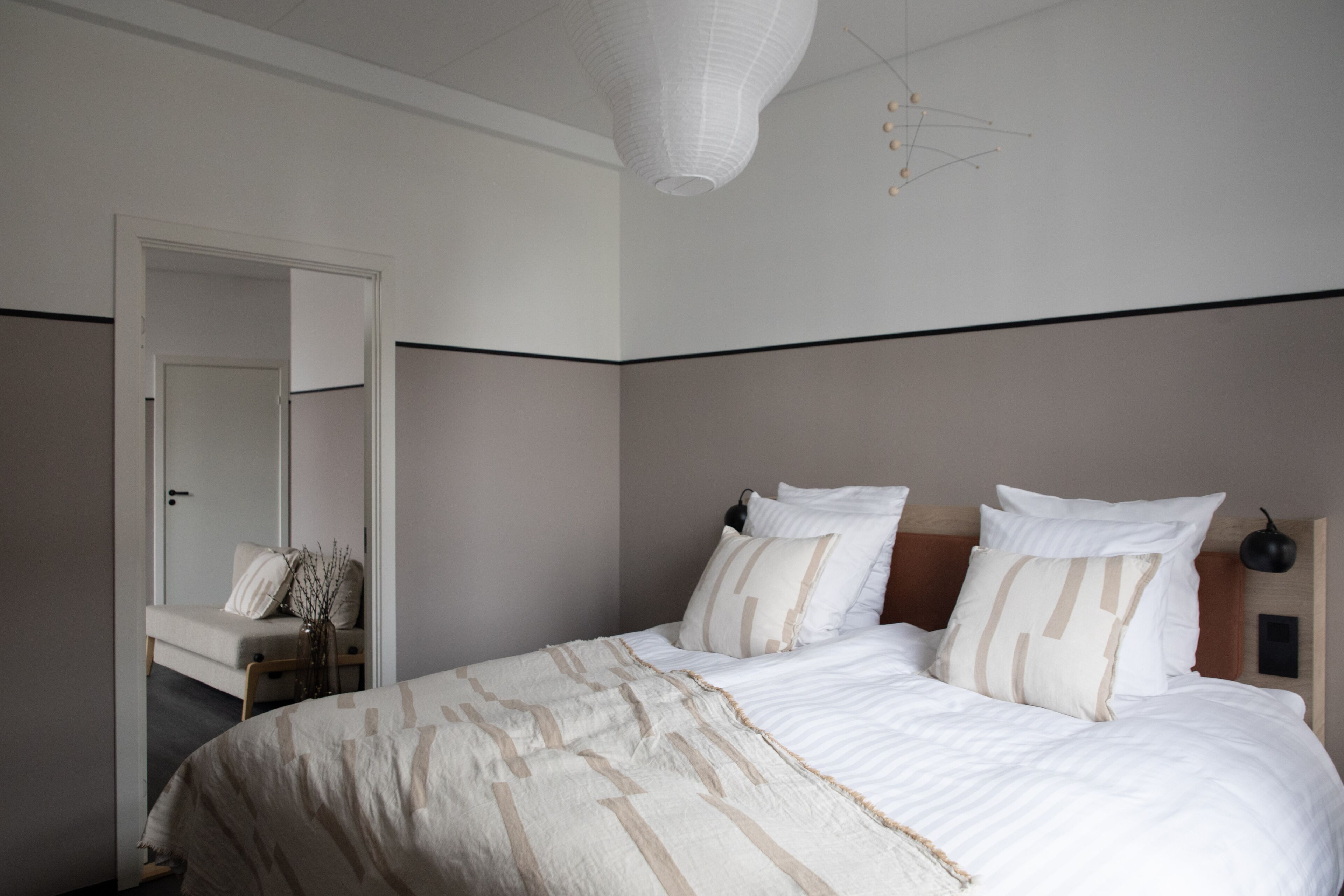 Ein Schlafzimmer mit einem großen Bett, einem Nachttisch, einem Spiegel und einer Pendelleuchte.