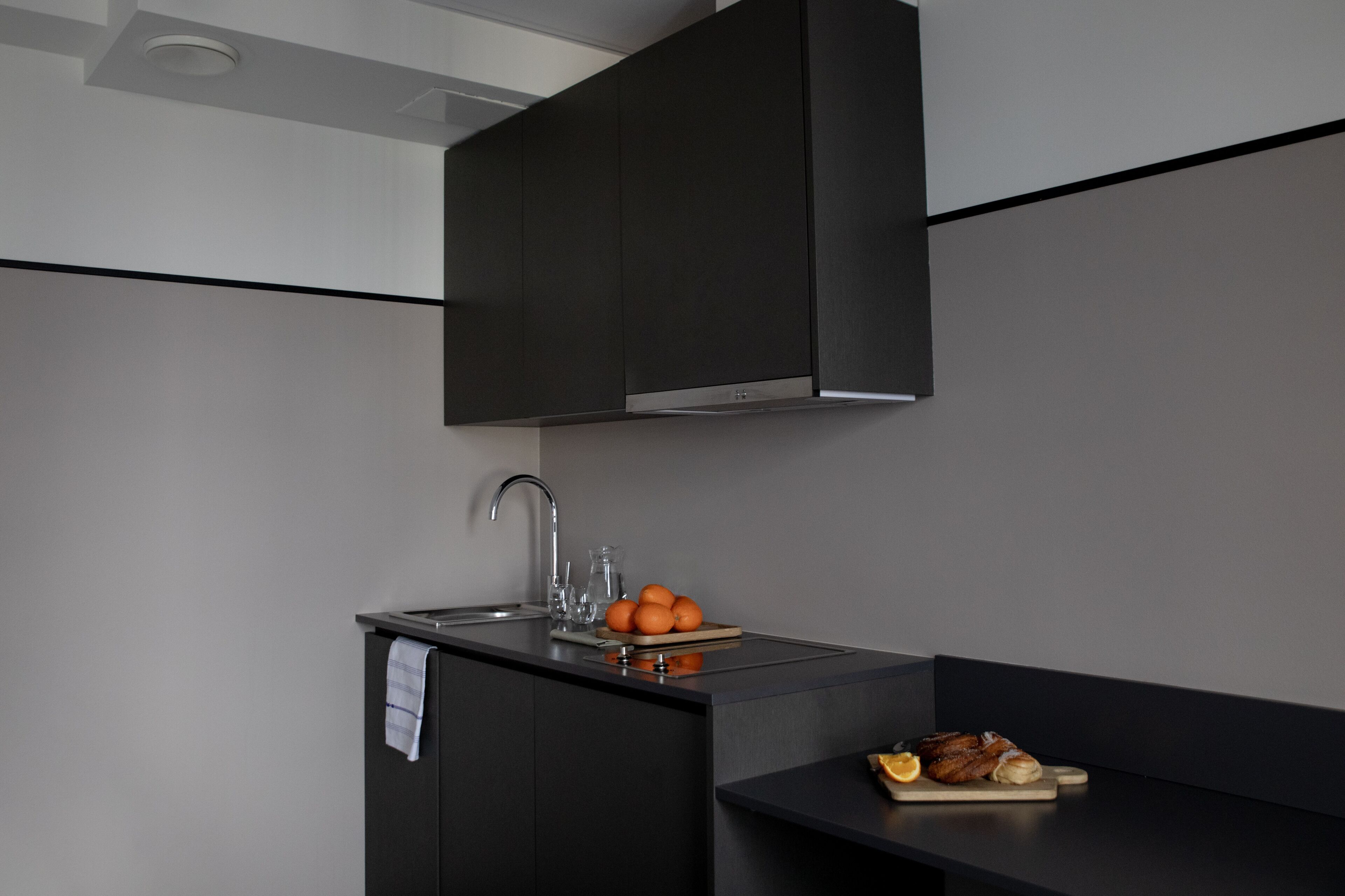 A modern kitchen with a dark countertop, a sink, and a bowl of oranges.