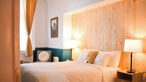 A hotel room with a wooden headboard, a bed with white bedding, two bedside lamps, and a nightstand with a lamp. - Hotel Terrasse Dufferin (Québec City)