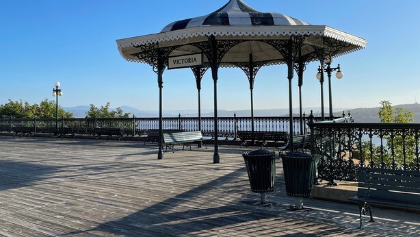 A gazebo with a Canadian flag, named "Victoria," on a wooden deck with benches and railings. - Hotel Terrasse Dufferin (Québec City)