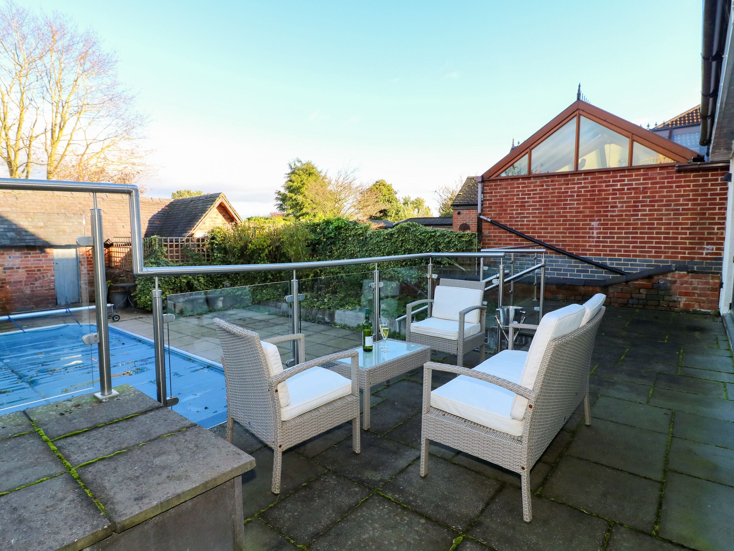 Eine Dachterrasse mit Gartenmöbeln, einer Glasbrüstung und einem Schwimmbecken.