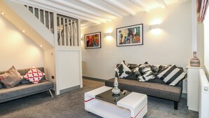 Ein modernes Wohnzimmer mit einem grauen Sofa, einem weißen Couchtisch und einer Treppe mit weißen Geländern.