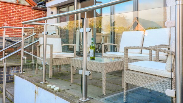Ein Balkon mit Korbmöbeln und Glasgeländern.