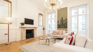 A living room with a fireplace, sofa, coffee table, and large windows. - Beautiful Belgravia by Underthedoormat (London)