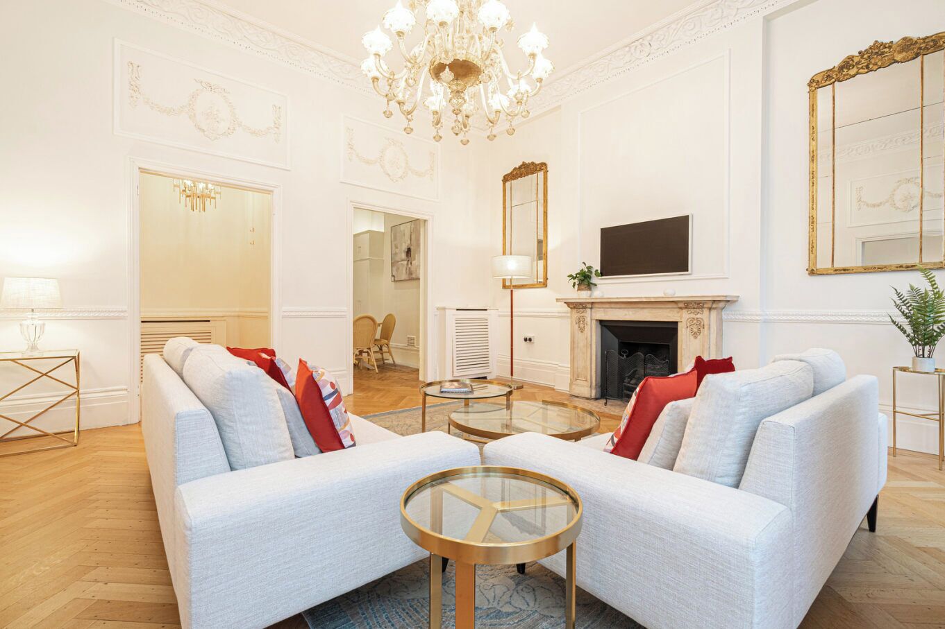 A spacious living room with a fireplace, a large mirror, and a chandelier.