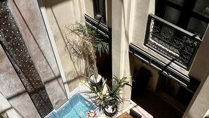 An outdoor pool area with a sun lounger, a small table, and a potted plant. - Riad Pourpre Medina (Marrakech)