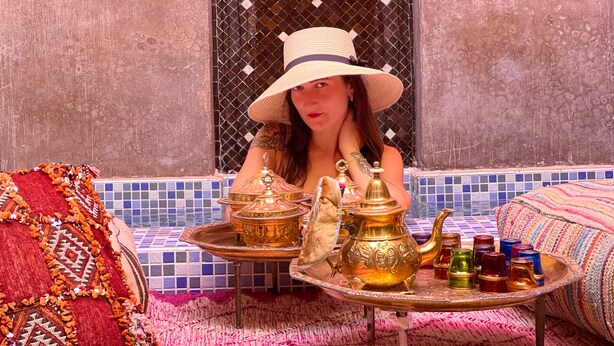 A room with a tiled floor, a patterned rug, a sofa, and a table with decorative items. - Riad Pourpre Medina (Marrakech)