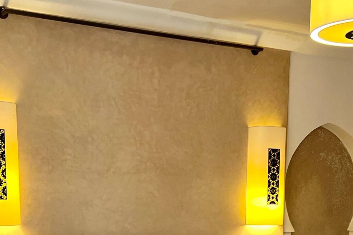 A hotel room with a large bed, a headboard, and two wall-mounted lamps.