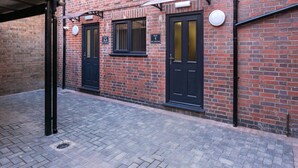 Un bâtiment en briques avec deux portes noires, chacune portant un numéro d’appartement.