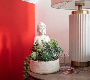 En Buddhastatue med en potteplante ved siden af en lampe på et bord.