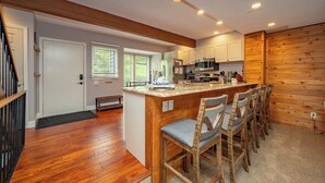 A kitchen with wooden bar stools, a central island, and built-in appliances.