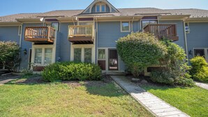 A two-story residential building with a front porch, a covered entryway, and a small front yard with a pathway.